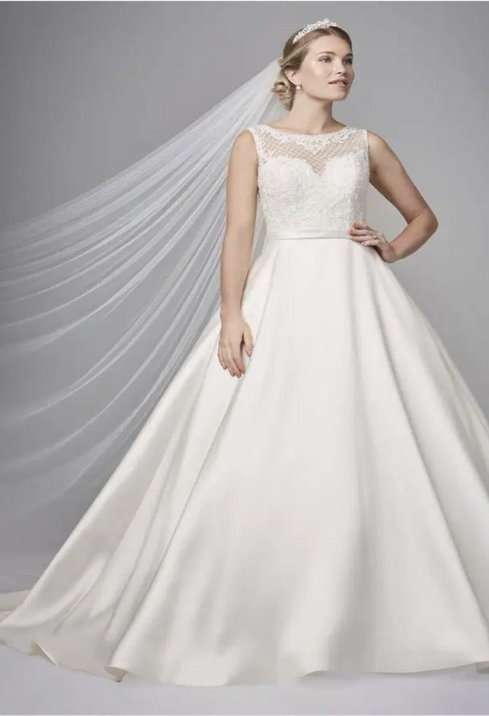 Beautiful Anna Sorrano Gianna is an a-line silhouette, lace and satin wedding gown with a detachable bow detail on the back. This dress boasts an illusion back, sweetheart neckline and a chapel length train.