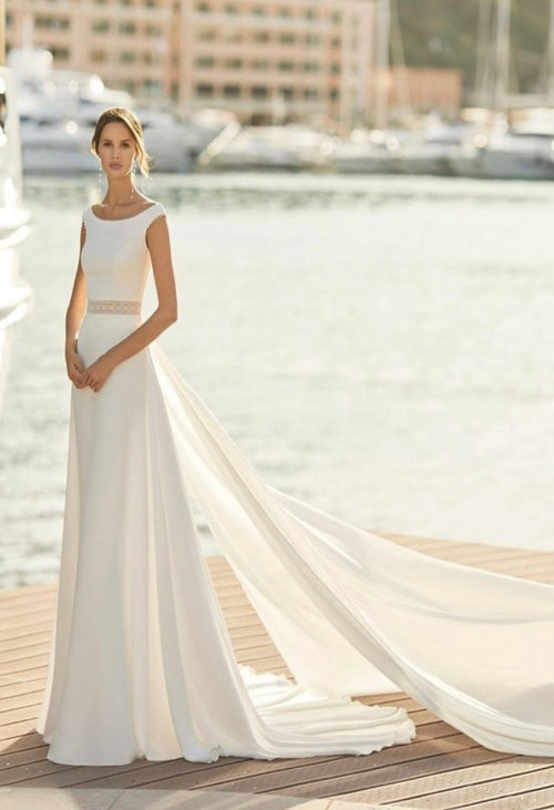 Aire Barcelona Ibis, Sheath-style wedding dress in crepe with lace edging. With bateau neckline, sheer lace edging on waist and detachable train