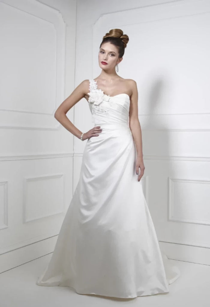 Stunning Kelsey Rose 10002A is an ivory satin bridal gown with one shoulder and an a-line silhouette. Size 12, chapel train, with back button detail. New condition. Available to view in store.